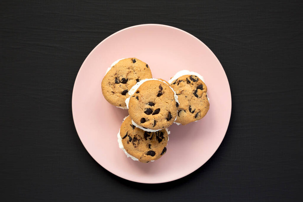 Homemade Chocolate Chip Cookie Ice Cream Sandwich on a pink plate on a black surface, top view. Overhead, from above, flat lay. - Fotoğraf, Görsel