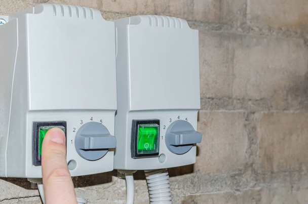 El dedo de las personas enciende el botón verde para poner el sistema de calefacción en producción. - Foto, imagen