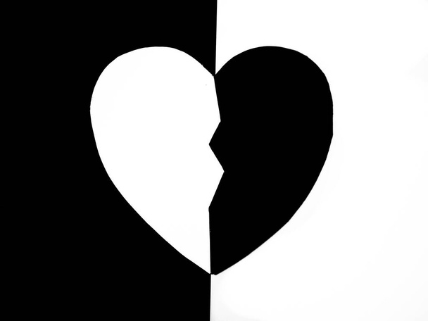Mitad papel blanco medio negro cortado corazón sobre fondo blanco y negro. Concepto de dualismo. - Foto, Imagen