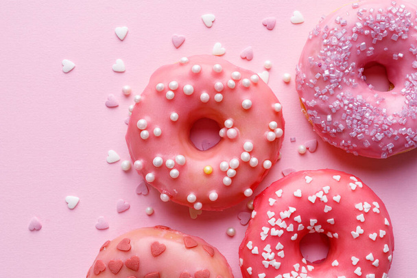Rosafarbene Donuts mit Zuckerguss und Zuckerstreusel auf pastellrosa Hintergrund von oben. eine Idee für einen Valentinstag leckeres Dessert - Foto, Bild