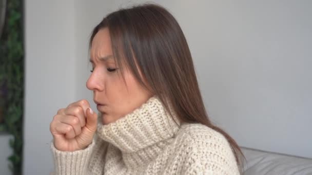 Mujer joven enferma con tos y dolor de garganta. Mujer enferma tosiendo en casa. Gripe, dolor de garganta, infección del tracto respiratorio, neumonía o bronquitis síntomas - Imágenes, Vídeo