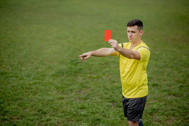 Angry football referee showing a red card and pointing with his hand on penalty. - Fotografie, Obrázek
