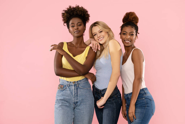 Photo of three funny cute multi-ethnic girls friends posing isolated over pink pastel studio background. - Photo, Image