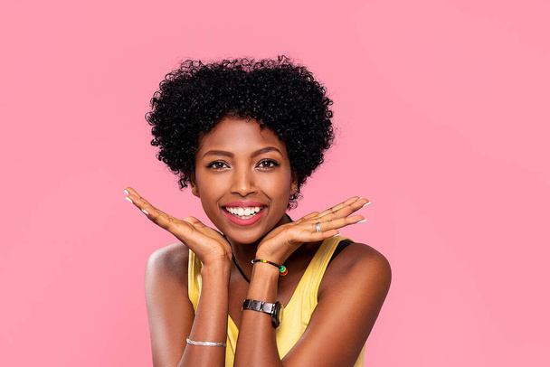 Happy young african woman with beautiful smile posing on pink pastel studio background. Attractive afro girl with glamour makeup. - Fotografie, Obrázek