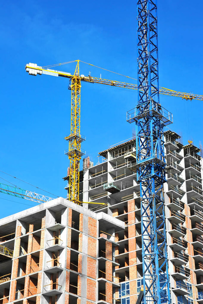 Kraanvogel en gebouw in aanbouw tegen blauwe lucht - Foto, afbeelding