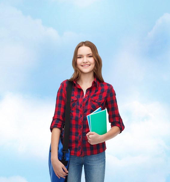 Smiling female student with bag and notebooks - Foto, Bild