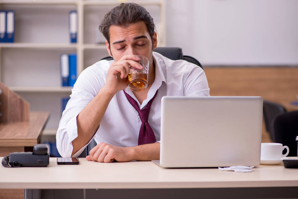 若い男性社員が事務所でアルコールを飲む - 写真・画像