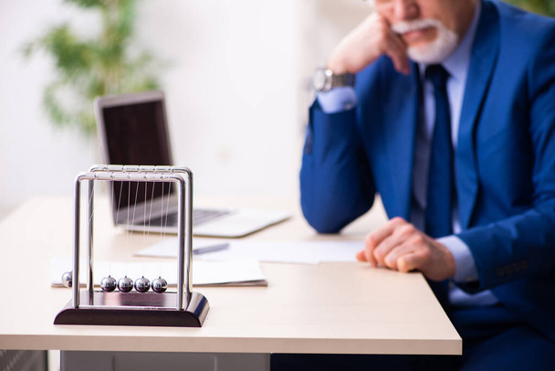 Old male employee businessman and meditation balls on the desk - Φωτογραφία, εικόνα
