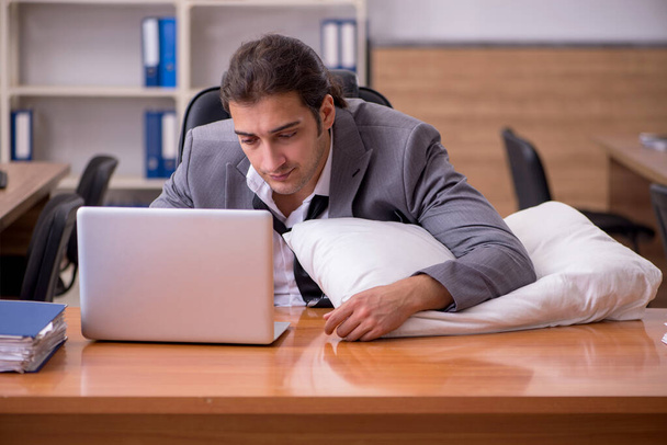 Fiatal férfi munkavállaló alszik a munkahelyen - Fotó, kép