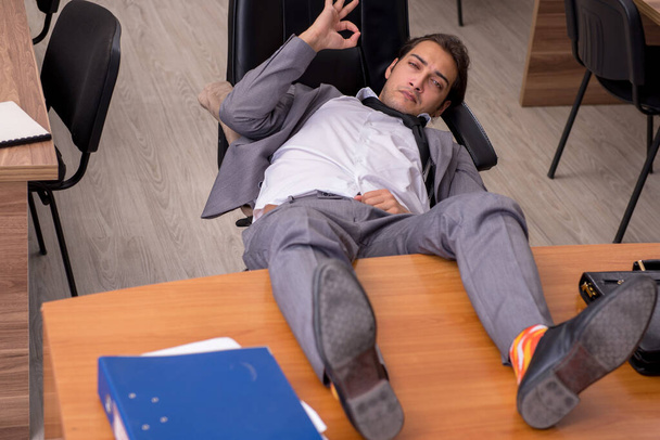 Nuori miespuolinen työntekijä nukkuu työpaikalla - Valokuva, kuva