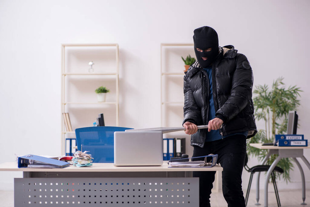 Молодой грабитель-мужчина в офисе - Фото, изображение