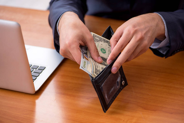 Young male employee holding wallet in remuneration concept - Photo, Image