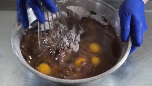 Massa de farinha para bolos de chocolate em uma tigela grande ingredientes, o chef começa a misturá-los com um batedor - Filmagem, Vídeo