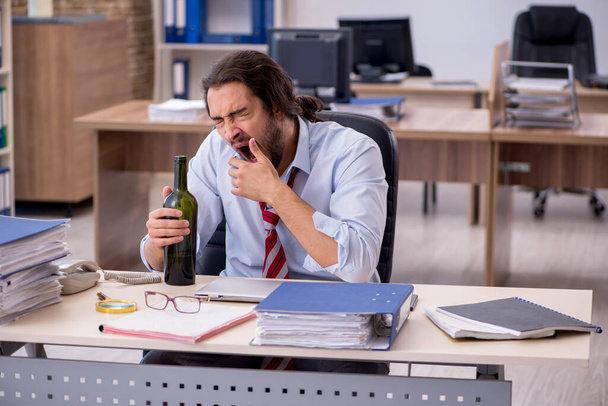 Empleado joven que bebe alcohol en la oficina - Foto, imagen