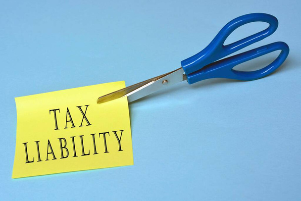 Olló, amely elvágja a sárga jegyzettömböt adókötelezettség szöveggel - Fotó, kép