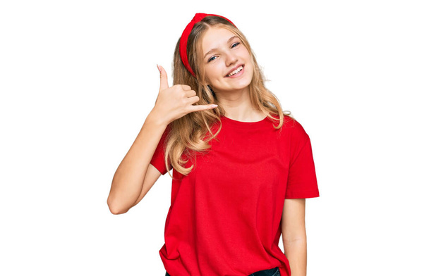 Kaunis nuori valkoihoinen tyttö yllään rento punainen t paita hymyillen tekee puhelimen ele käsin ja sormin kuin puhua puhelimessa. käsitteiden välittäminen.  - Valokuva, kuva