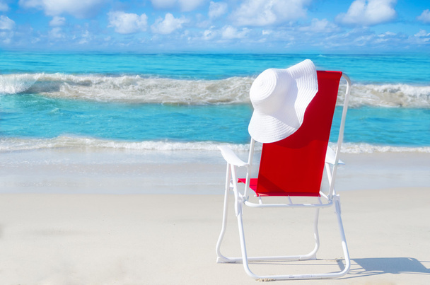 Chaise de plage avec chapeau blanc au bord de l'océan
 - Photo, image