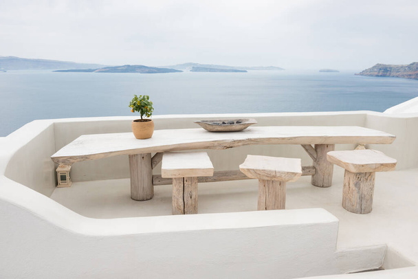 Mesa con sillas, mar Egeo y volcán en el fondo - Foto, Imagen