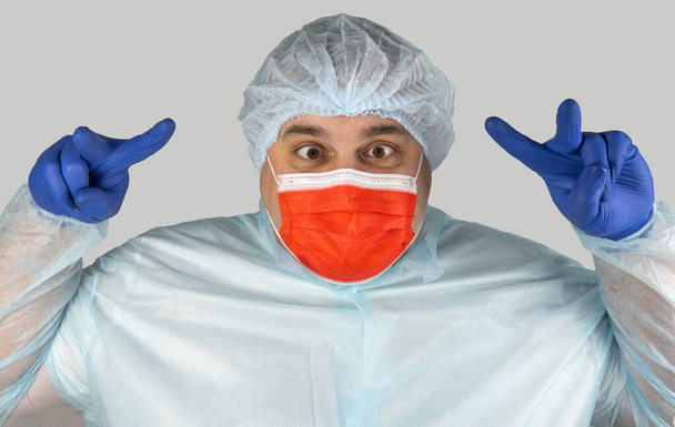 crazy surgeon, a strange doctor in a red medical mask. the medical worker is having fun and grimacing. aggressive and inadequate medical officer makes hand gestures. practitioner has gone mad - Fotoğraf, Görsel