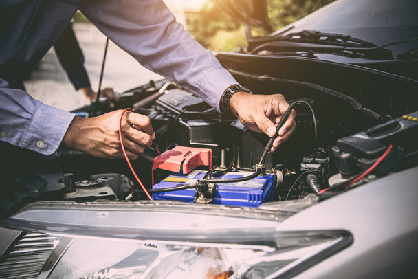 Az autószerelő közeli keze mérőműszert használ az akkumulátor ellenőrzésére. Fogalom az autó javítási és karbantartási (0 replies). - Fotó, kép