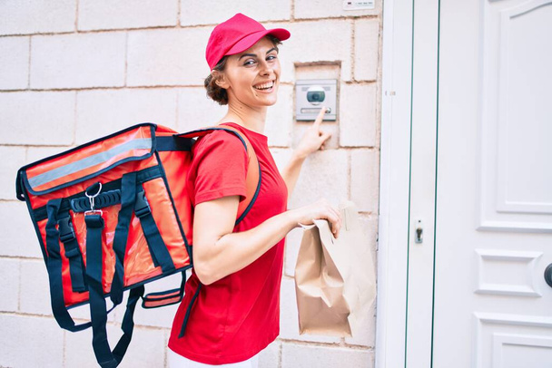 Delivery business worker woman wearing uniform smiling happy knocking on the door - Foto, Imagen