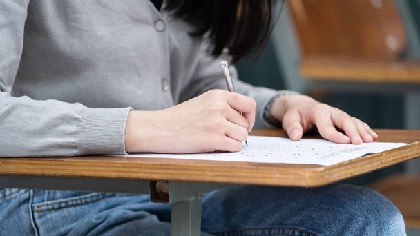 Zbliżenie studentki piszącej na notatniku umieszczonym na drewnianym pulpicie - Zdjęcie, obraz