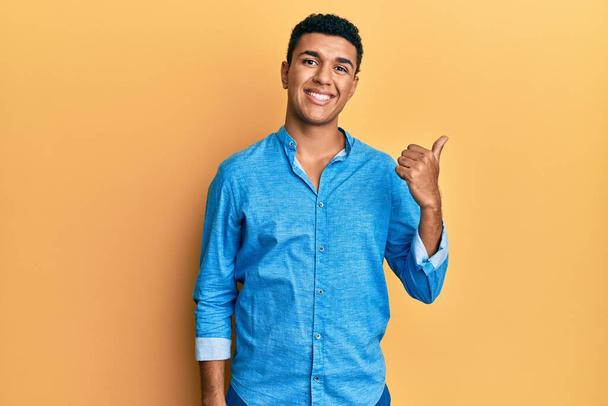 Young arab man wearing casual clothes smiling with happy face looking and pointing to the side with thumb up.  - Φωτογραφία, εικόνα