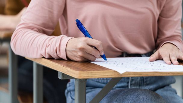 Közelkép fiatal női egyetemi hallgatók írásban a választ a vizsgák a válaszlapot az osztályteremben. - Fotó, kép