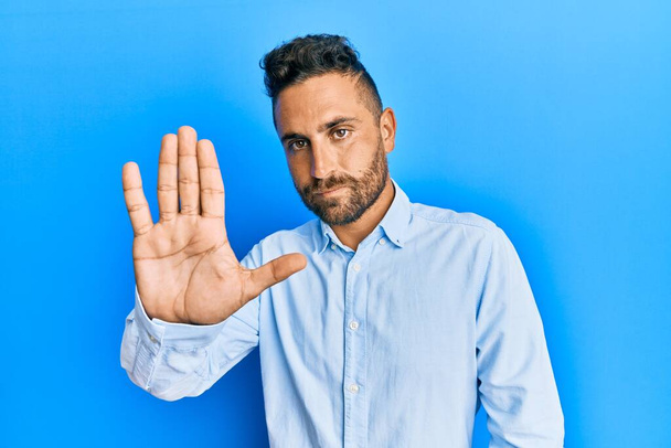 Handsome man with beard wearing casual clothes doing stop sing with palm of the hand. warning expression with negative and serious gesture on the face.  - Foto, afbeelding