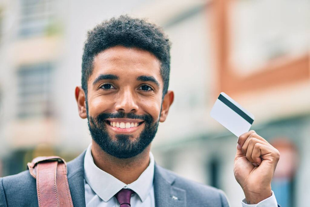 Genç Afrikalı Amerikalı iş adamı, şehirde kredi kartı tutarken mutlu gülümsüyor.. - Fotoğraf, Görsel