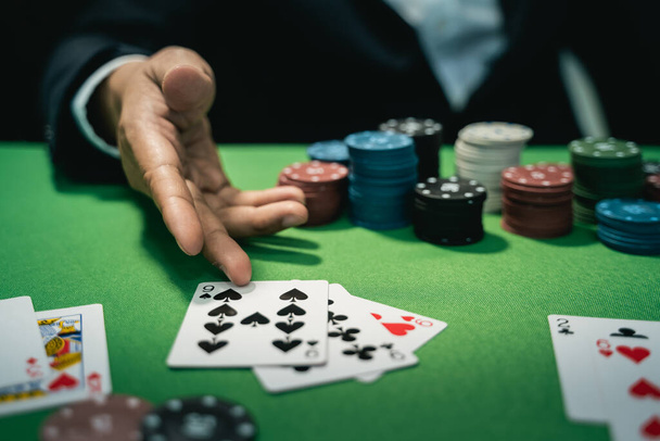Satıcı ya da krupiye, poker konsepti olan bir masanın arka planında kumarhanede poker kartları karıştırıyor. - Fotoğraf, Görsel