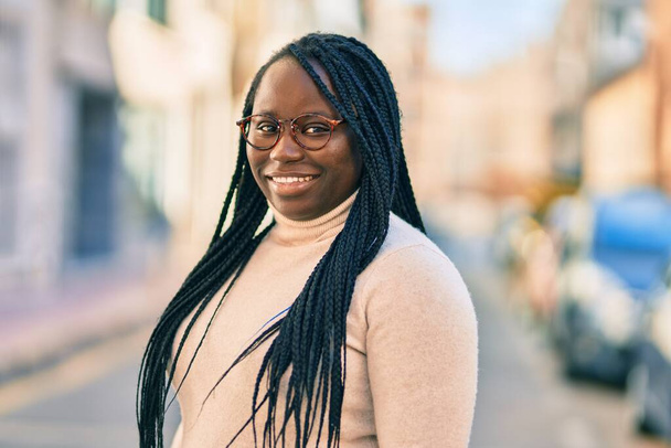 Joven mujer afroamericana sonriendo feliz de pie en la ciudad. - Foto, Imagen