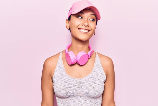 Jovem mulher ouvindo música usando fones de ouvido olhando para o lado, relaxar pose perfil com rosto natural e sorriso confiante.  - Foto, Imagem