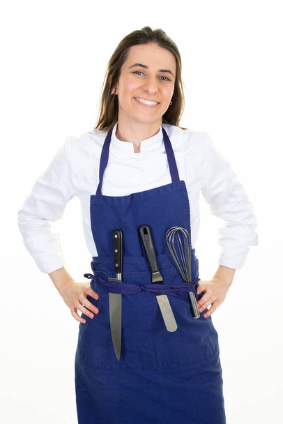 vrouwelijke chef gebak in keukenschort met mes en zweep op riem in witte achtergrond - Foto, afbeelding