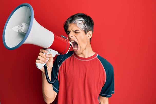 Молодой человек кричит с гневом и энергией через мегафон - Фото, изображение