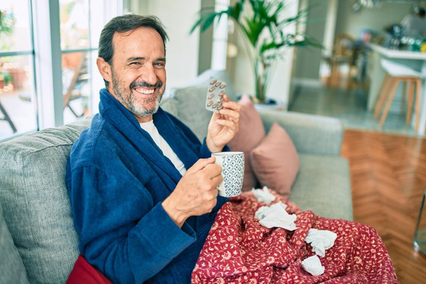 Középkorú férfi rosszul érzi magát a hideg és láz otthon, beteg influenza betegség ül a kanapén - Fotó, kép