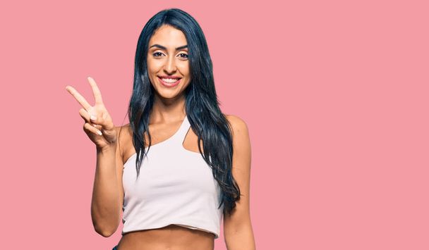Beautiful hispanic woman wearing casual clothes showing and pointing up with fingers number two while smiling confident and happy.  - Foto, Imagem