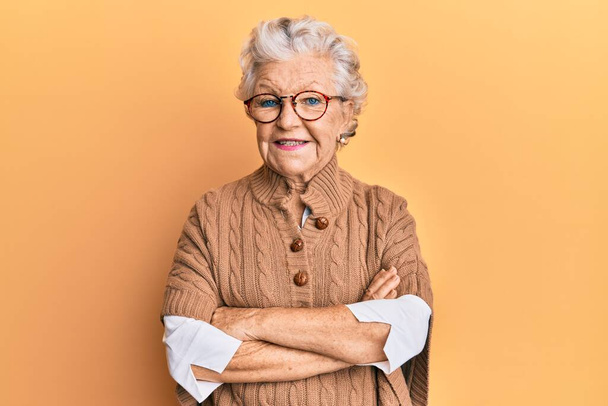 Oudere grijsharige vrouw met casual kleren en een bril vrolijk gezicht glimlachend met gekruiste armen kijkend naar de camera. positieve persoon.  - Foto, afbeelding