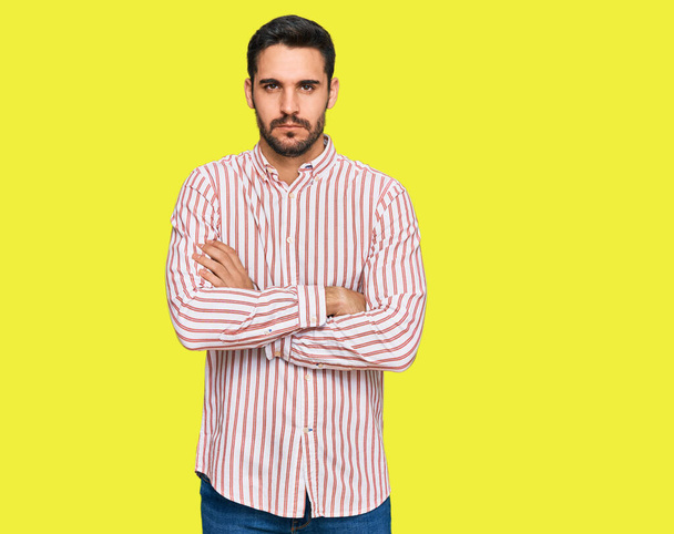 Junger hispanischer Mann im Businesshemd skeptisch und nervös, ablehnender Gesichtsausdruck mit verschränkten Armen. Negative Person.  - Foto, Bild