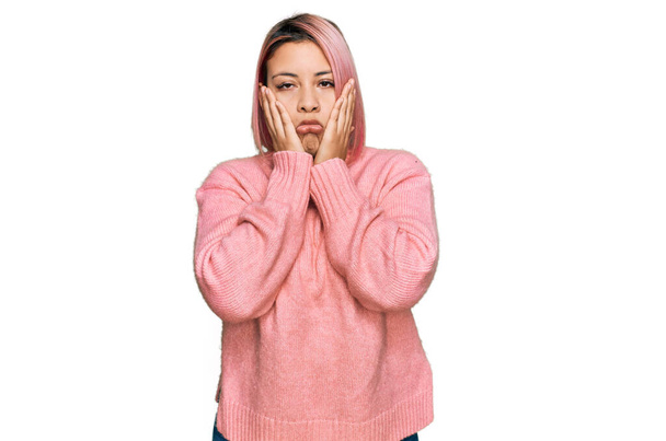 Mulher hispânica com cabelo rosa vestindo camisola de inverno casual mãos cansadas cobrindo rosto, depressão e tristeza, chateado e irritado por problema  - Foto, Imagem