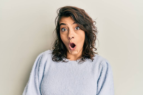 Mujer hispana joven vistiendo suéter casual de invierno asustada y conmocionada con expresión sorpresa, miedo y cara excitada.  - Foto, Imagen