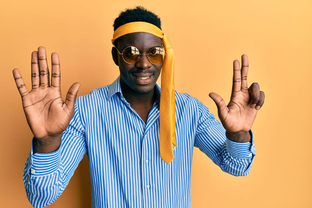 Handsome black man drunk wearing tie over head and sunglasses showing and pointing up with fingers number eight while smiling confident and happy.  - Photo, Image