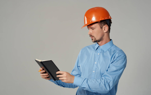 πολιτικός μηχανικός σε πορτοκαλί σκληρό καπέλο κρατώντας έγγραφα στα χέρια σημειωματάριο εργασίας των επιχειρήσεων - Φωτογραφία, εικόνα