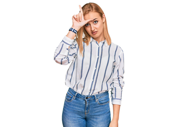 Beautiful caucasian woman wearing casual clothes making fun of people with fingers on forehead doing loser gesture mocking and insulting.  - Photo, Image