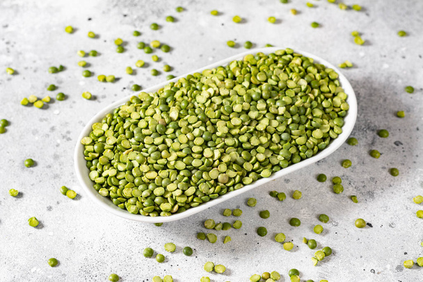 Green peas. Dry green peas in a white ceramic bowl on the light gray kitchen table. Organic Natural Vegetarian Product - Фото, зображення