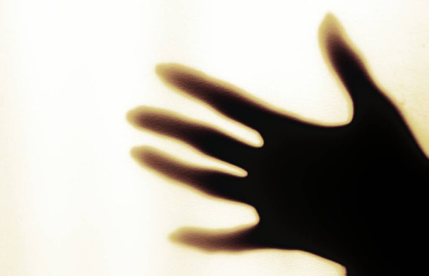 een wazige schaduw van een hand op een geschilderde muur, de schaduw van de hand van een vrouw van dichtbij - Foto, afbeelding
