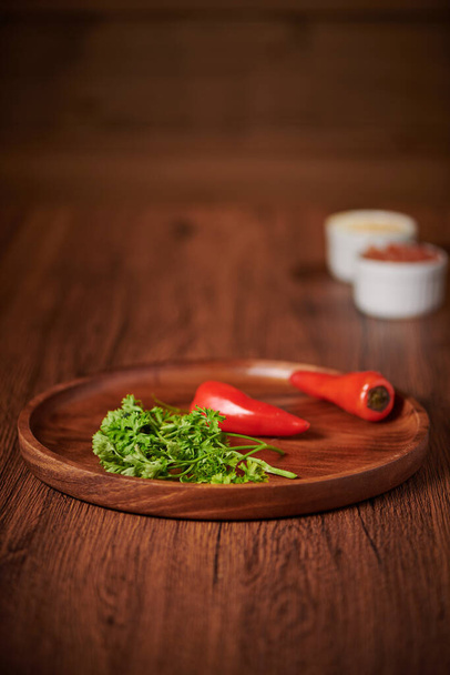 A vertical shot of fresh peppers and parsley on a wooden tray - Foto, imagen
