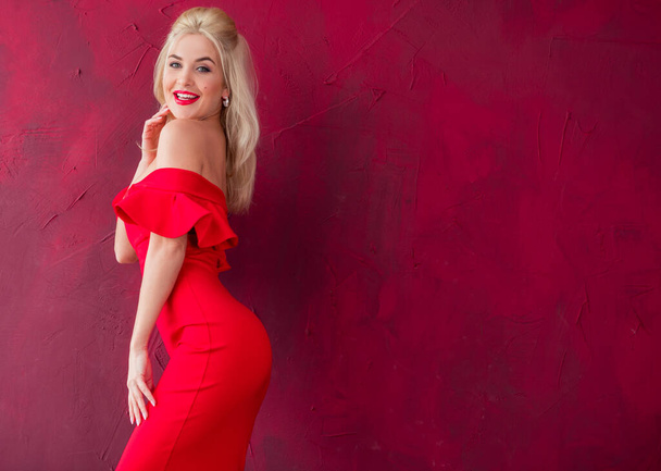 Smyslná a romantická krásná blondýnka pózující v červených stylových šatech Pěkná dáma s jasnými vlasy v koktejlových šatech - Fotografie, Obrázek