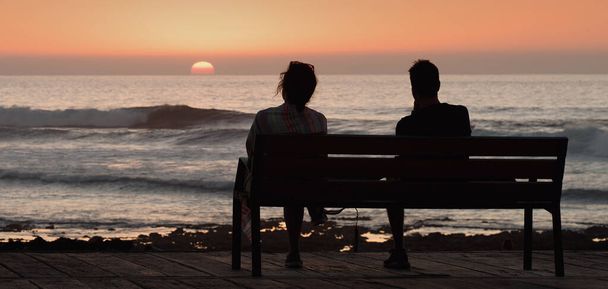Silueta pareja romántica en un banco junto al mar - Foto, Imagen