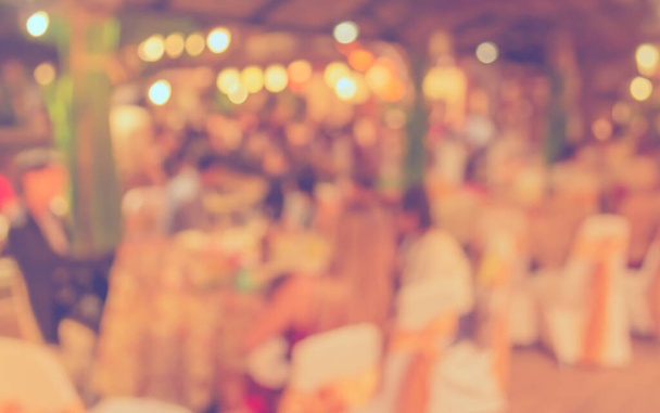 Imagen borrosa abstracta de Conjunto de mesa de comedor grande para bodas, cenas o eventos de festivales con hermosa decoración de luces dentro de un gran salón para uso de fondo. (tono vintage) - Foto, imagen
